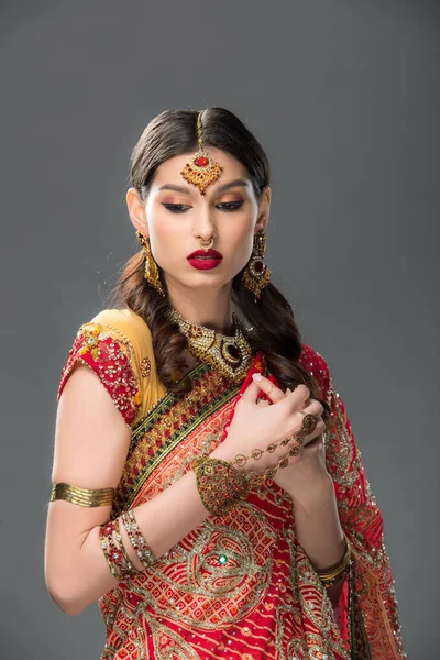 Привлекательная индийская женщина в традиционной одежде и аксессуарах, изолированная на сером — стоковое фото