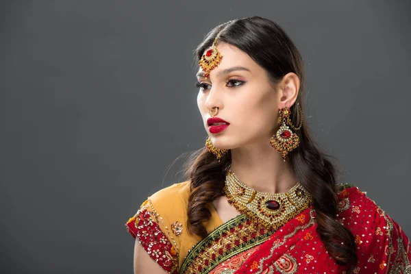 Atractiva mujer india en sari y bindi en la cabeza, aislado en gris - foto de stock