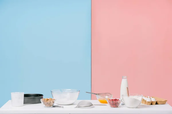 Vários ingredientes de cozinha e utensílios na mesa de cozinha branca no fundo bicolor — Fotografia de Stock