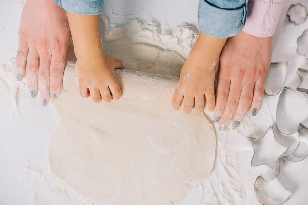 Vue recadrée de la mère et de l'enfant déroulant la pâte ensemble sur fond blanc — Photo de stock