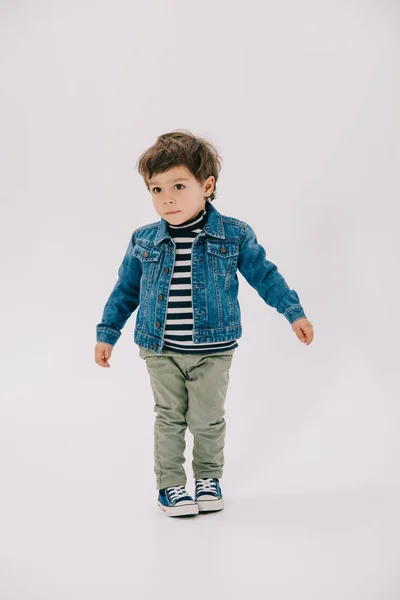 Adorable niño en chaqueta azul y pantalones vaqueros verdes aislados en blanco - foto de stock