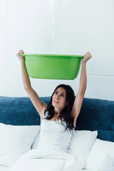 Mulher estressada com bacia lidando com danos causados pela água no quarto — Fotografia de Stock
