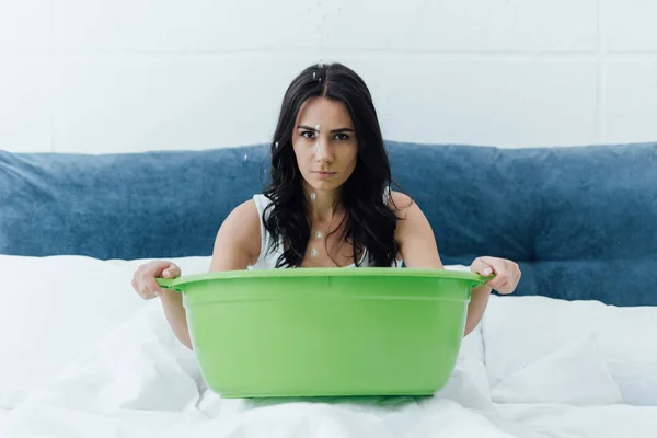 Sad girl with green basin dealing with leak in bedroom — Stock Photo