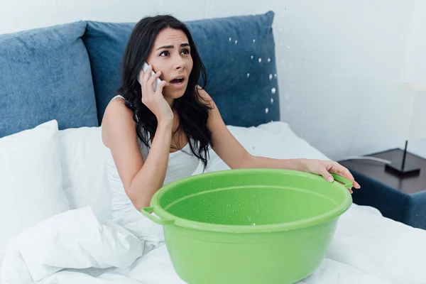 Verängstigte Frau spricht auf Smartphone und sieht Wasserleck im Schlafzimmer — Stockfoto