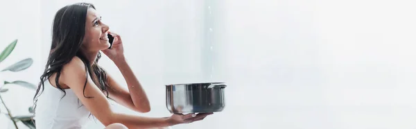 Frau telefoniert mit Smartphone und hält Topf unter Wassertropfen — Stockfoto