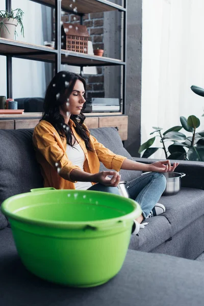 Relaxed woman sitting on sofa in yoga pose — Stock Photo