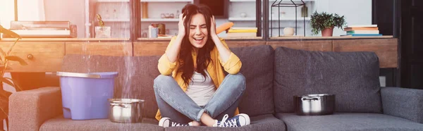 Mujer estresada sentada en el sofá y gritando con los ojos cerrados - foto de stock