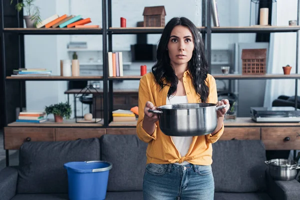 Young woman in yellow shirt holding pot in living room — Stock Photo