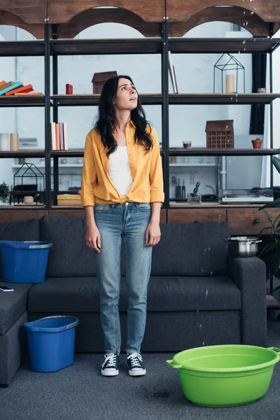 Full length view of sad brunette woman looking at leaking ceiling — Stock Photo