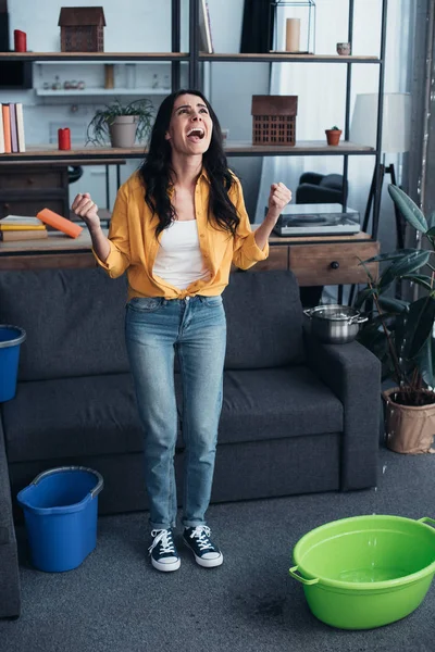 Кричащая женщина в джинсах смотрит на протекающий потолок — стоковое фото