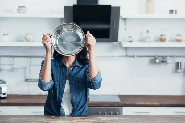 Woman holding steel pot in front of face in kitchen — Stock Photo