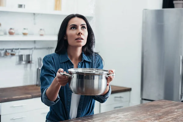 Woman in denim shirt holding steel pot and looking up — Stock Photo