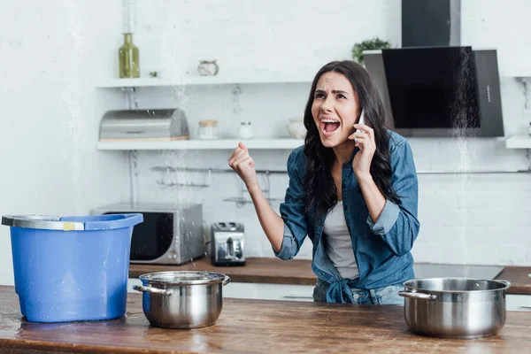 Femme en colère appelant plombier pendant la fuite dans la cuisine — Photo de stock