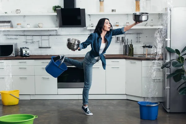 Visão de comprimento total da mulher sacudida em jeans lidando com vazamento de água na cozinha — Fotografia de Stock