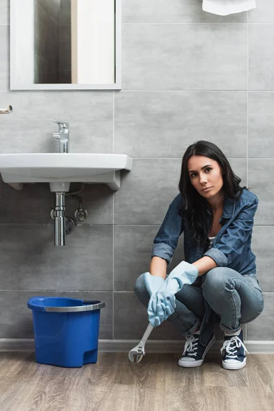 Chica cansada con llave inglesa sentada en el baño - foto de stock