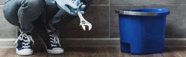 Cropped view of woman in rubber gloves holding wrench — Stock Photo