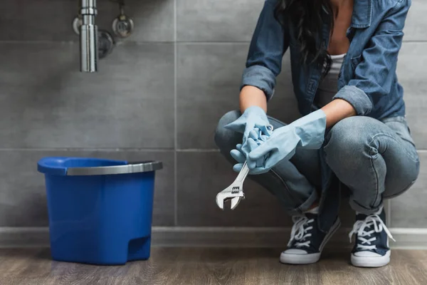 Partial view of woman in rubber gloves holding wrench — Stock Photo