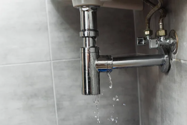 Tubería de acero dañada en el baño sobre fondo gris - foto de stock