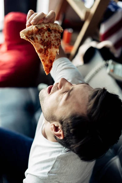 Bêbado homem colocando na boca fatia de deliciosa pizza — Fotografia de Stock