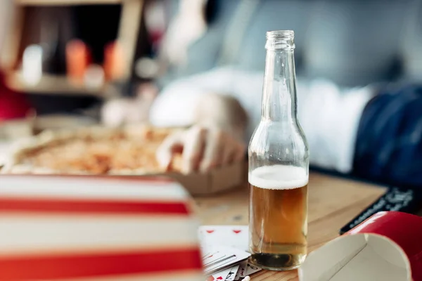 Selective focus of bottle of beer with man on background — Stock Photo