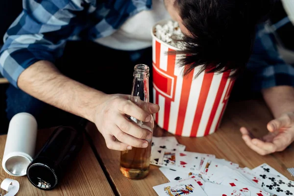Cropped view of man with head in popcorn box holding bottle — Stock Photo