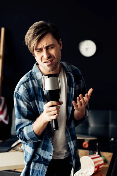 Drunk man holding bottle and singing at home — Stock Photo