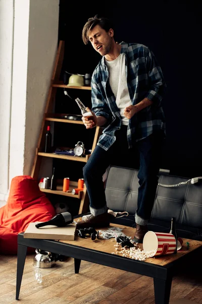 Drunk man standing on coffee table and singing after party at home — Stock Photo