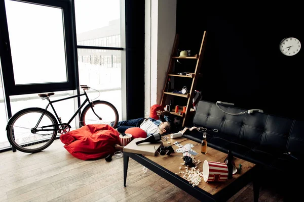 Messy living room with bottles and popcorn on coffee table — Stock Photo