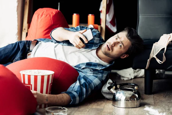 Drunk man lying on bean bag and holding smartphone — Stock Photo