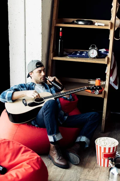 Drunk man drinking beer and holding acoustic guitar at home — Stock Photo