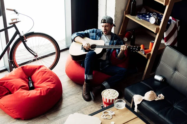 Handsome man singing while playing acoustic guitar at home — Stock Photo