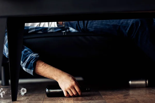 Cropped view of man lying on sofa near bottles after party — Stock Photo