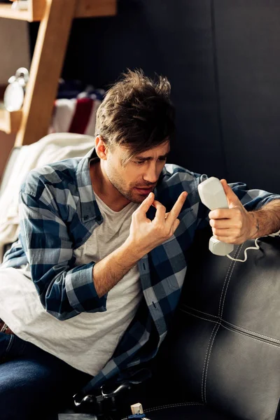 Пьяный мужчина держит телефон и показывает средний палец дома — стоковое фото