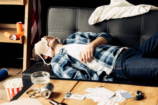 Man sleeping on sofa with bra on face after party — Stock Photo