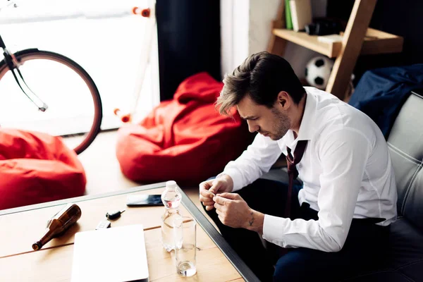 Man in suit suffering from hangover sitting in living room and holding pill — Stock Photo