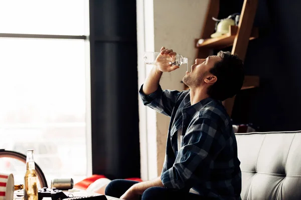 Schöner Mann trinkt Wasser, während er auf dem Sofa sitzt — Stockfoto