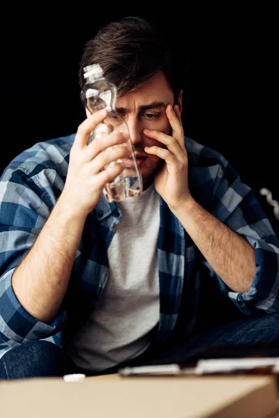 Bel homme souffrant de gueule de bois tenant une bouteille d'eau — Photo de stock