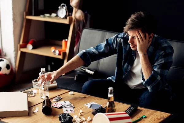 Man suffering from hangover holding head near bottle of water — Stock Photo