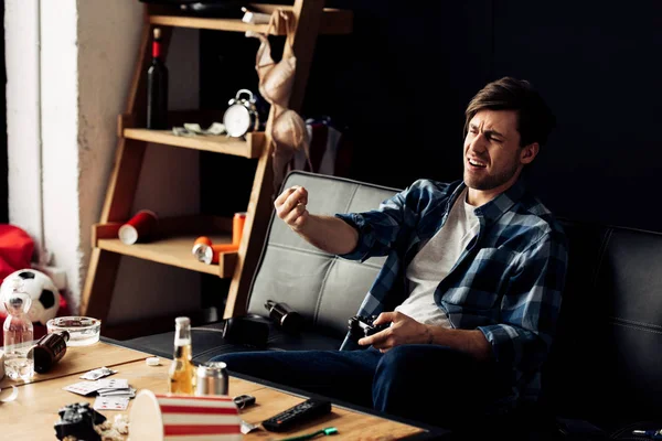 Handsome man gesturing while playing video game at home — Stock Photo