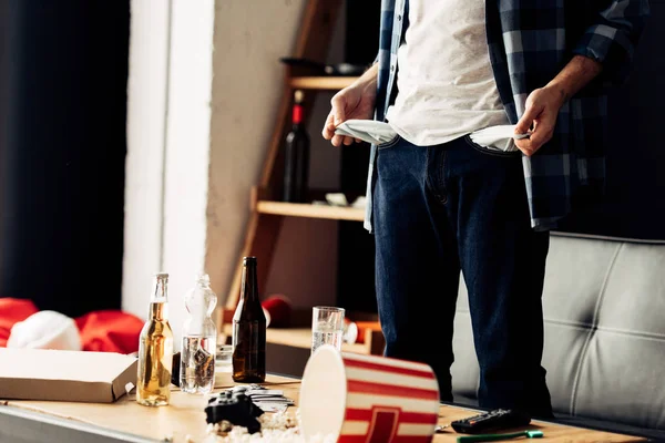 Cropped view of man standing and showing empty pockets after party — Stock Photo