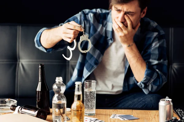 Man covering face while looking at handcuffs after party — Stock Photo