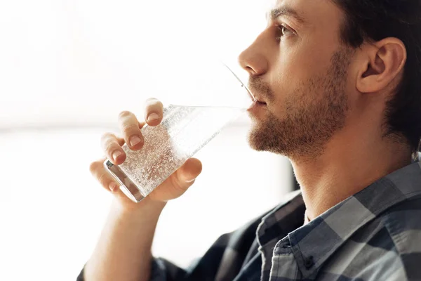 Bel homme tenant verre et eau potable — Photo de stock