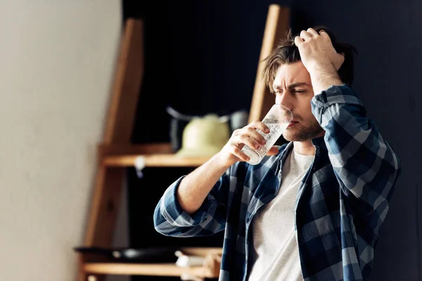 Hombre borracho sosteniendo vidrio y agua potable después de la fiesta - foto de stock