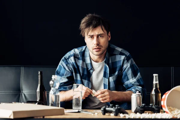 Exhausted man suffering from hangover holding aspirin and glass of water in hands — Stock Photo