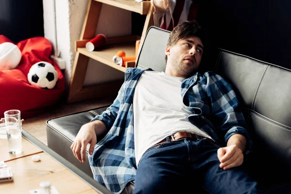 Tired man lying on sofa and having hangover after party — Stock Photo