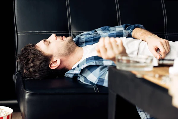 Selective focus of tired man lying on sofa and having hangover — Stock Photo