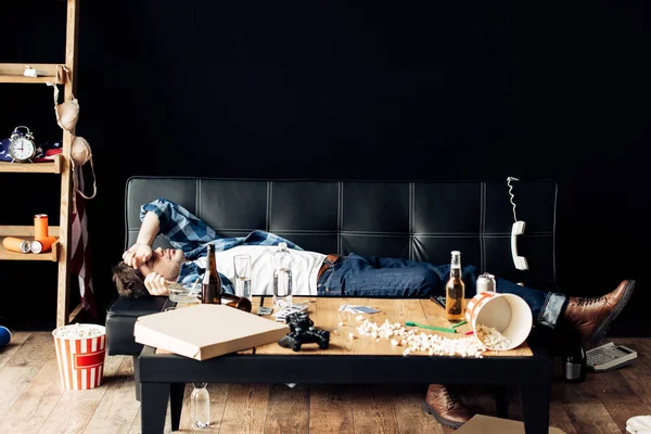 Exhausted man lying on sofa after party at home — Stock Photo