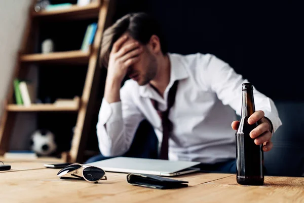 Selective focus of bottle in hand of man having headache after party — Stock Photo