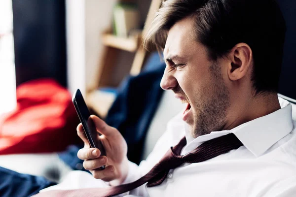 Angry man in suit screaming at smartphone after party — Stock Photo