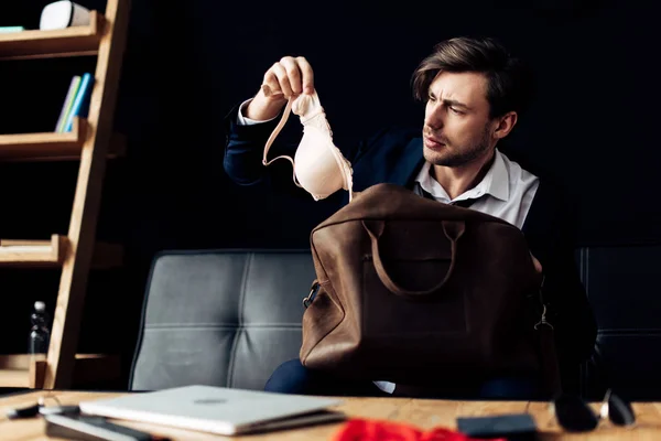 Verwirrter Mann im Anzug schaut nach Party im Büro auf BH — Stockfoto